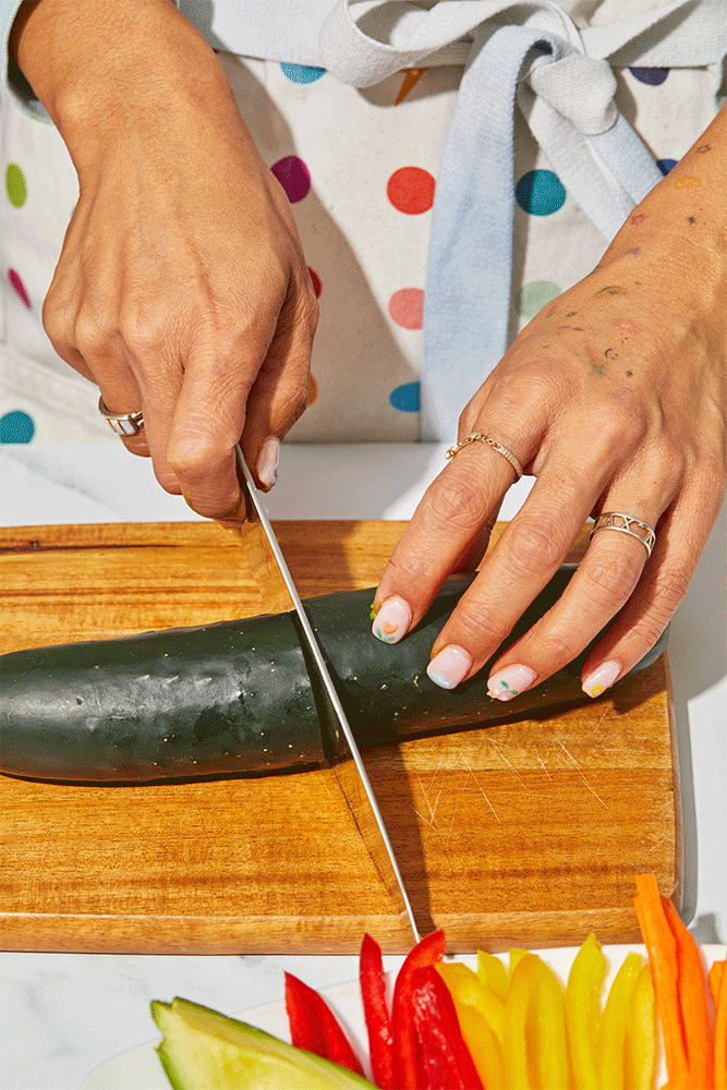 Four photos show how to make cucumber veggie rolls. The instructions are as follows: Cut two large cucumbers in half. Using an apple corer, remove the center of the cucumber. Fill the hollowed cucumbers with avocado slices, red bell pepper, yellow pepper and carrot until they are filled to the brim. Then cut your vegetable-filled cucumbers into half-inch rounds.