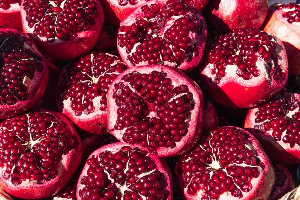 several ripe red pomegranates with cut surface, close-up background