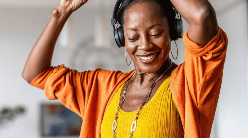 She wears headphones and dances at home with a smile