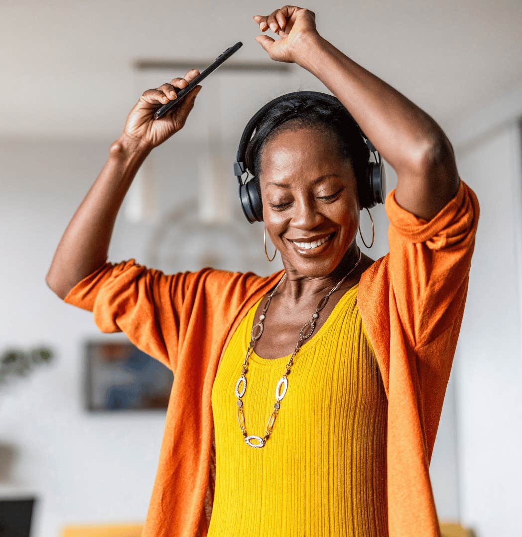 She wears headphones and dances at home with a smile